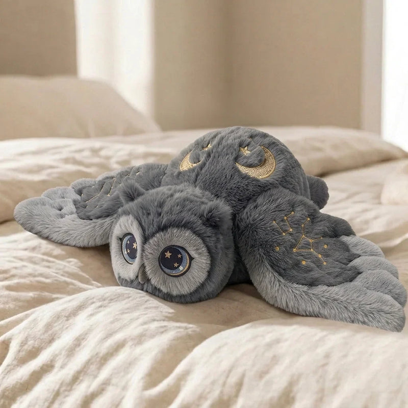 Hibou gris brodé posé sur un lit